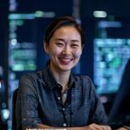 皇冠体育安全技术总监李慧敏，面带微笑坐在代码屏幕前，专注数据安全与加密技术领域